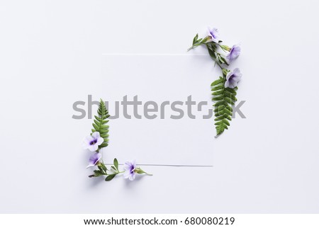 Artistic mockup for your artwork with beautiful flowers and leaves and empty card shot from the top. Flat lay minimalistic composition.