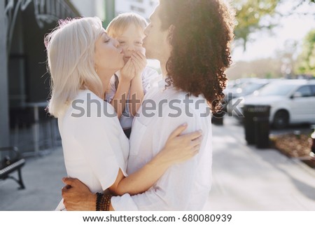 dad mom and a little boy with blond hair walking around the city and enjoying the sunshine, multi family black and white