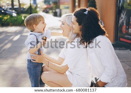 dad mom and a little boy with blond hair walking around the city and enjoying the sunshine, multi family black and white