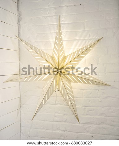 Decorative lamp in the form of a star in bright interiors. Lighting on the wall.