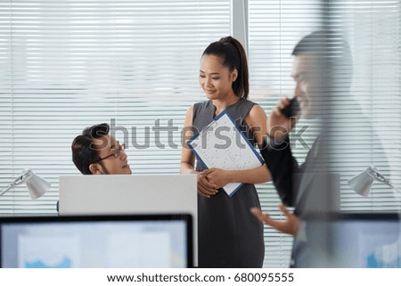 Pretty Asian business lady consulting with her coworker