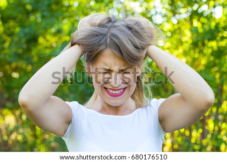 Picture of a very angry young woman having a breakdown  holding her head and hair outdoor