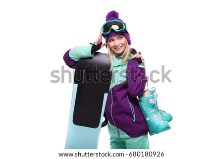 isolated on white, attractive caucasian girl in purple ski outfit and sunglasses hold blue snow boots and snowboard, look at camera, lies on board