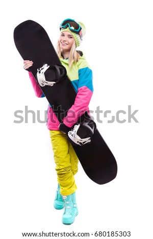 vertical picture, isolated on white, attractive  young caucasian girl in colorful ski outfit, blue snow boots and yellow trousers hold black snowboard