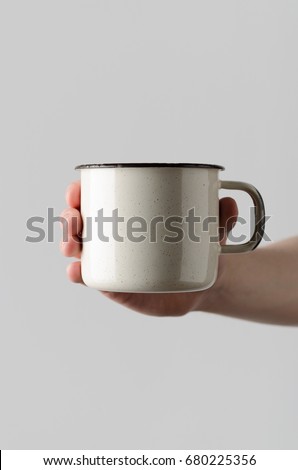 White Enamel Mug Mock-Up - Male hands holding an enamel mug on a gray background