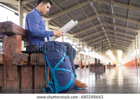man traveler with backpacker look searching location map at trainstation, travel concept