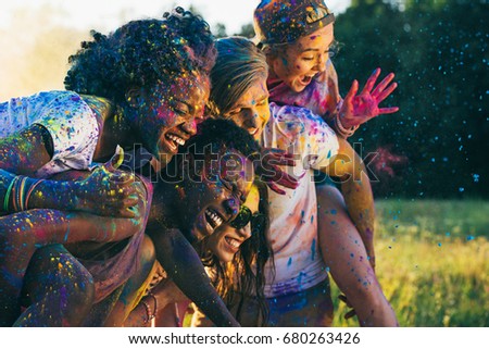 multicultural happy friends piggybacking together at holi festival Royalty-Free Stock Photo #680263426