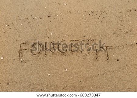 Handwriting  words "FORGET IT." on sand of beach.