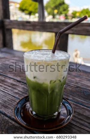 Ice green tea with milk on top on wooden table