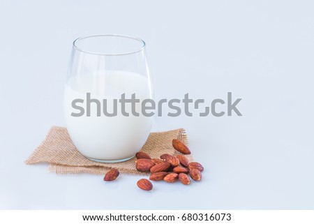Almond milk in a glass   with  almond seeds on marble table. vintage color style.