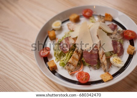 Cesar salad on white plate with black stripe on wooden background 