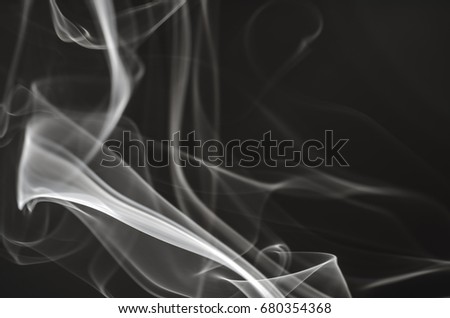 Thick, scenic clouds of smoke. From incense, or cigarettes, or cigars. Indoors. In the rays of sunshine on a dark background. Psychedelic mood. Close up. Colorful abstract background.