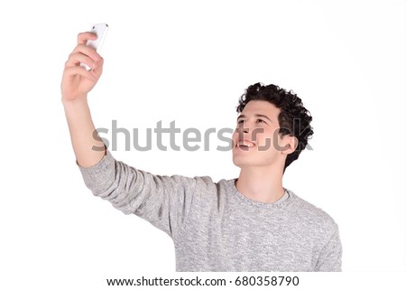 Portrait of a young man taking selfie with smartphone. Isolated white background.
