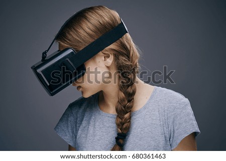 Woman in glasses of virtual reality on a gray background portrait 3d                               
