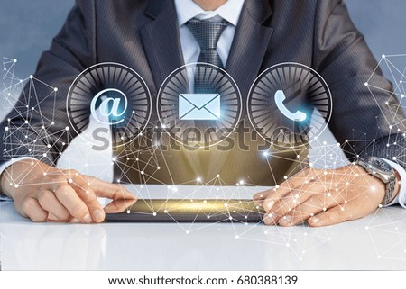 The businessman at the table and the contact us icons on virtual screen.