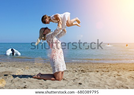 Mother and daughter have fun and kissing on the beach. Summer holidays, travel, vacation concept.