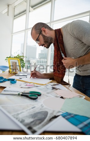 Male designer drawing sketch while standing at table in studio