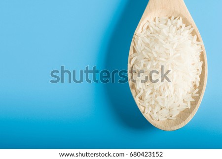 Raw Rice on Wood Spoon in blue background