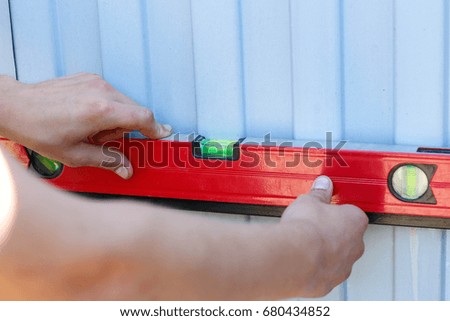 A man checks a smooth surface level. Red construction level.