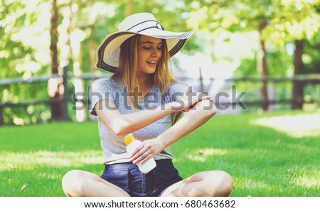 Young woman a bottle of sunblock outside on a summer day Royalty-Free Stock Photo #680463682