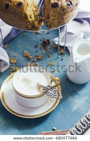 Top view of a breakfast menu with  a Cup of hot cappuccino, nuts ciambella cake, over a rusty blue bakgroud
