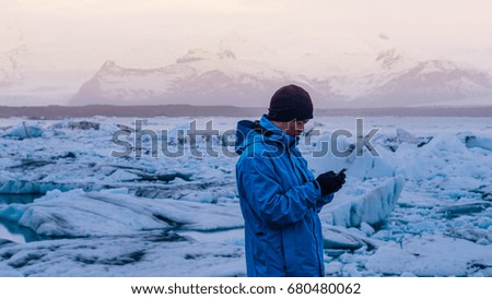 Asian man using smart phone at jokulsarlon, Glacier lagoon Iceland.  World travel destination