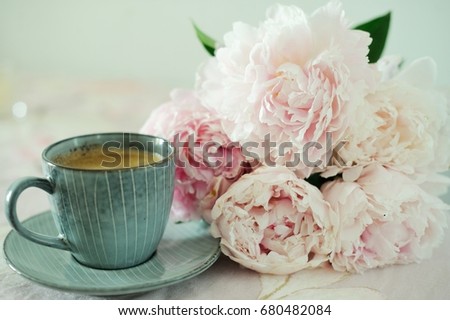 Still life with cup of coffee, cakes and flowers (peonies) on light  table.