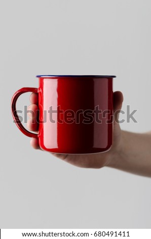 Red Enamel Mug Mock-Up - Male hands holding an enamel mug on a gray background
