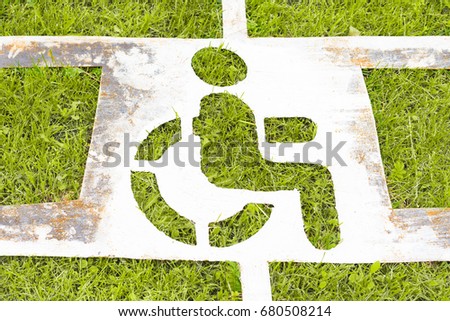 An old stencil sign of a disabled man on grass, protection, freedom and rights of disabled people concept