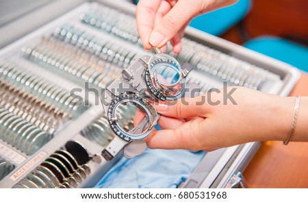 Optician female hands choose lenses from set of corrective lens indicating on the plates of the shape: concave, convex, cylindrical. Abstract background to ophthalmology concept. Selective focus Royalty-Free Stock Photo #680531968