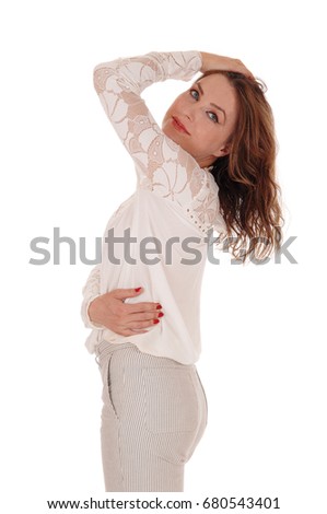 A young beautiful woman standing in a lace blouse and trousers with
on hand on her head in profile, isolated for white background.

