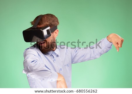A young guy with a beard on a green background in the eyes of virtual reality.