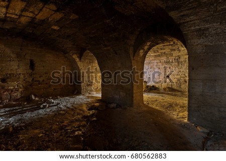 An old abandoned tunnel in an underground wine cellar. Entrance to catacombs. Dungeon An old stone fortress. As a creative background for staging dark design. Mystic interior of an ancient dungeon
