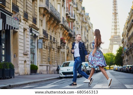 Romantic couple running across the street with Eiffel tower in background in Paris, France