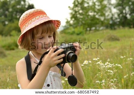 baby photographer (a little girl) with a camera on the background of  nature
