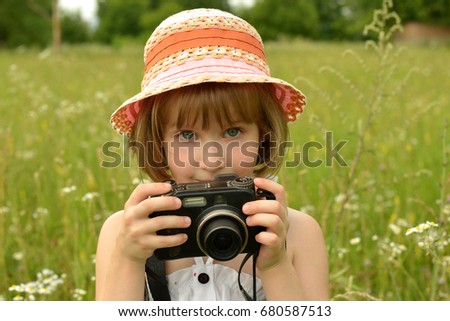 portrait of a baby photographer (a little girl) with a camera on the background of nature.