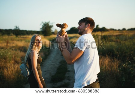 Romantic Couple at Sunset with small puppy of chihuahua dog. Two people in love at sunset or sunrise. Man and woman on field