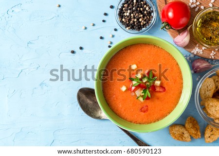 Summer cold soup gazpacho with parsley and vegetables on blue concrete background. Spanish cuisine. Top view. Copy space.