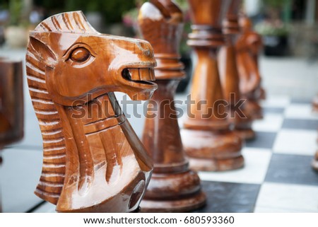 Giant garden chess set set out for a game. Life size chess pieces and checkered pattern floor tiles.