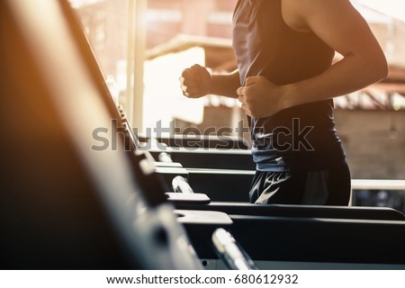 Man running in a modern gym on a treadmill concept for exercising, fitness and healthy lifestyl.lowkeylight.vintage tone.selective focus. Royalty-Free Stock Photo #680612932