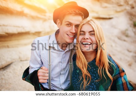 Handsome man and beautiful woman smiling into the camera in the middle of a sandy canyon.