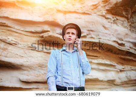 Attractive man is standing in the middle of a sand quarry and making a call from a smartphone.