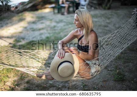 Beautiful blonde girl with hat sitting on a lounge at the beach in summer