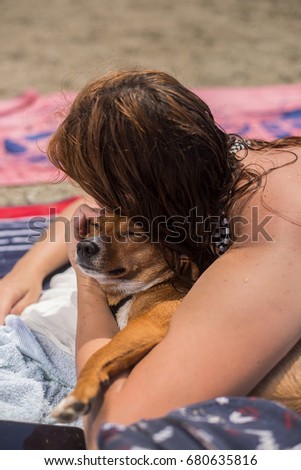 Beautiful redhead girl and her dog lying at the beach in summer
