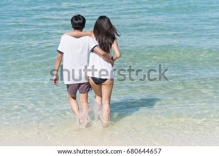 view of happy romantic young couple walking at the beach