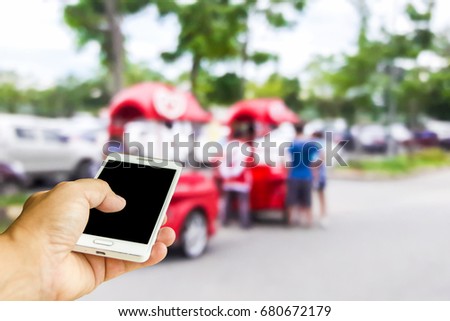 Man use mobile phone, blur image of car selling ice cream as background.