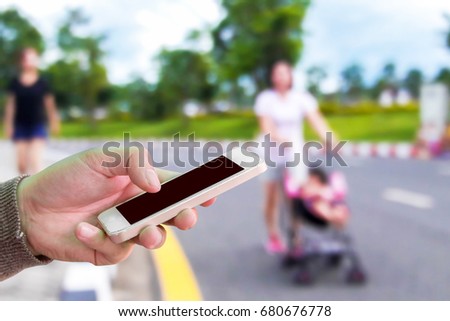 Man use mobile phone, blur image of people exercising in the park as background.