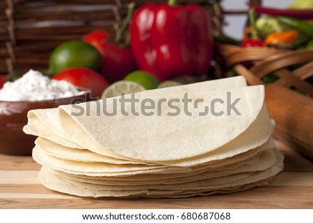 Soft taco shells on a table with fresh vegetables 
