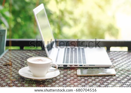 cup of coffee with notebook and smart phone on table at natural greening view in the morning, Happy work place concept
