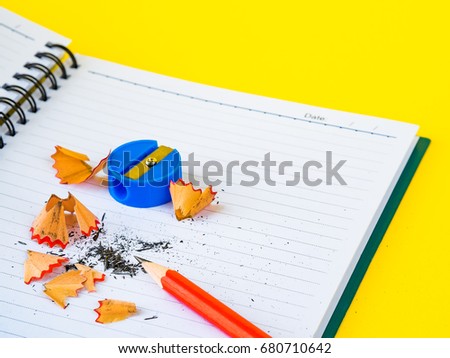 Office accessories including note book, red pencil and blue sharpener on yellow background. Education and business concept.